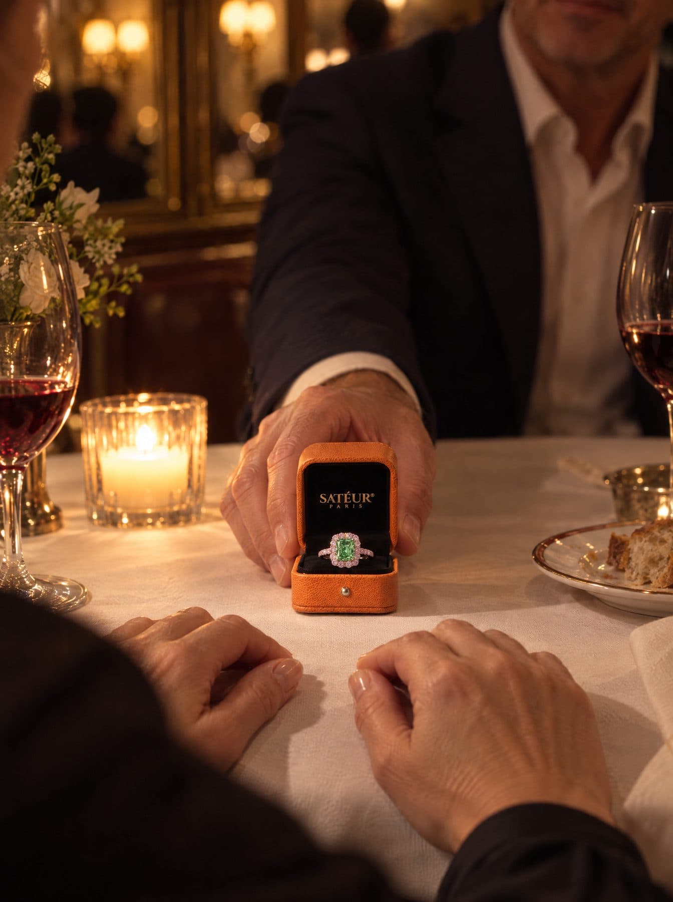 A man slides an open orange Satéur box across a candlelit table